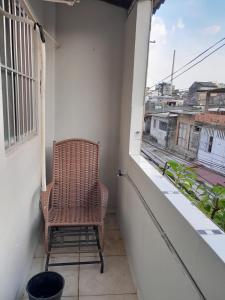 a wicker chair sitting on a balcony with a window at Suíte com 2 camas de casal para Cop30 in Belém