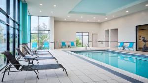 a pool in a hotel with chairs and tables at Staybridge Suites Aurora East by IHG in Aurora