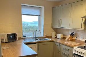 eine Küche mit einer Spüle, einer Mikrowelle und einem Fenster in der Unterkunft Cottage - Sleeps 4 - Pets Ok - Parking - Garden in Wooler