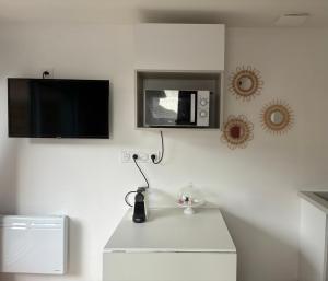 a white kitchen with a microwave and a tv on the wall at Maison in Lamonzie-Saint-Martin