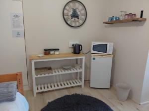 a kitchen with a microwave and a refrigerator and a clock at Cenikma Guest Suites - Family Room 1 in East London