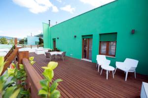 a deck with white chairs and a green building at Casa Iab in Arezzo
