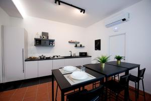 a kitchen with white cabinets and a black table and chairs at Casa Iab in Arezzo