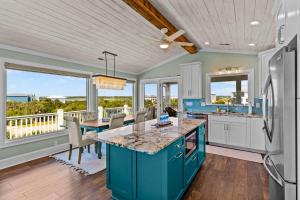 a kitchen with blue cabinets and a table with chairs at Sunny Second Row Beach and BIG views in Varnamtown