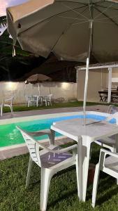 a white table and chairs with an umbrella next to a pool at Pousada Viver a Vida - No Centro Conservatória in Conservatória