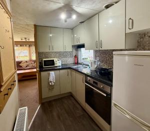 a kitchen with white cabinets and a white refrigerator at The Raven in Silloth
