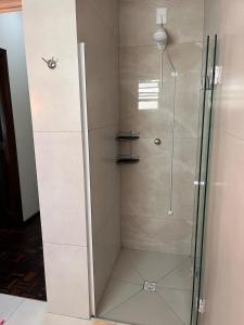 a shower with a glass door in a bathroom at Grünes Haus 2 quartos no centro in Pomerode +14 photos
