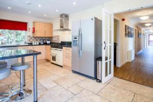 a large kitchen with a refrigerator and a table at The Barn - 4 Bedroom - Tyn-Y-Coed Farm - Cardiff in Creigiau