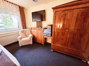 a bedroom with a large wooden cabinet and a chair at Hotel Elisabeth Ilse in Braunlage +94 photos