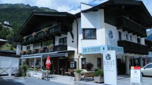 a large white building with balconies and tables and chairs at Heiners in Sölden