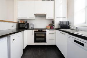 a white kitchen with white cabinets and a sink at Maison Loft Verzy - Nomad by Welkeys in Paris +10 photos