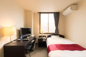 una camera d'albergo con un letto e una scrivania con un computer di Hotel SIMIZU a Tokamachi