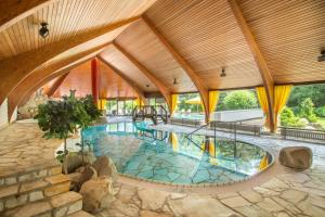 een groot zwembad in een gebouw met houten plafonds bij Romantik Hotel Stryckhaus in Willingen