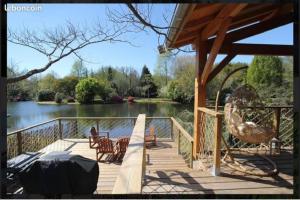 a wooden deck with chairs and a view of a lake at Lodge with pool in the heart of the Landes in Léon