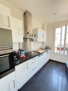 a kitchen with white cabinets and black counter tops at Parisian Apartment for 3 People - Paris Parc des Princes WiFi & Metro in Boulogne-Billancourt