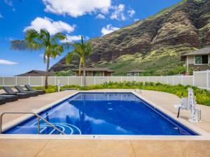 a swimming pool with a mountain in the background at Kalo Homes - Surfside Serenity in Makaha Valley