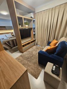 a living room with a blue couch and a tv at Travellar Apt 91 - Admirável - Monte Carmelo in Ribeirão Preto