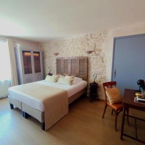 a bedroom with a large bed and a table and chair at Hôtel Mas Vidau Porte des Alpilles in Saint-Étienne-du-Grès +48 photos