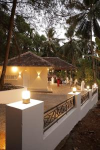 a white fence with candles in front of a house at Kurinjirappallil Farms Homestay in Paithalmala