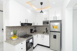 a kitchen with white cabinets and a stainless steel refrigerator at Cozy 1BR 1BA Bayahibe Getaway with Pool in Bayahibe