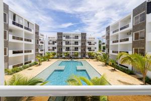an apartment building with a swimming pool and palm trees at Cozy 1BR 1BA Bayahibe Getaway with Pool in Bayahibe