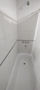 a white bathroom with a shower with a sink at Departamento Temporario Tucuman 3Personas Pileta in San Miguel de Tucumán
