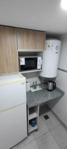 a kitchen with a counter with a microwave and a refrigerator at Departamento Temporario Tucuman 3Personas Pileta in San Miguel de Tucumán