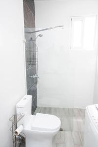 Un baño blanco con inodoro y ducha. en Stylish 1BR Condo in the Heart of Bayahibe w Pool, en Bayahibe