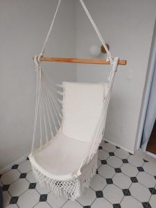 a white swinging chair in a room with a tiled floor at Santé Vivre L'expericénce, Búzios in Búzios