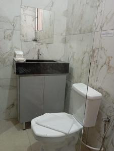 a bathroom with a toilet and a sink and a mirror at Ribeiro Flat in Araxá