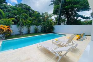 a swimming pool with two chairs and a table next to it at Bonita Beach Villa in La Ceiba