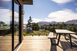 a wooden deck with a bench and a view of mountains at The Alpine 2-Bedroom Villa - Roam Lake Tekapo in Lake Tekapo