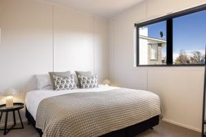 a white bedroom with a bed and a window at The Alpine 2-Bedroom Villa - Roam Lake Tekapo in Lake Tekapo