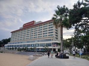 釜山にある해운대호텔 엘본더스테이の大きな建物とその前を歩く人々