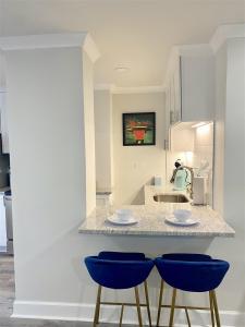 a kitchen with two blue chairs at a counter at 8th Floor Stylish Downtown Condo Private Balcony in Atlanta