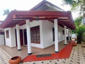 a white building with columns and a roof at Breeze Blows- Solitude Holiday Home in Matara