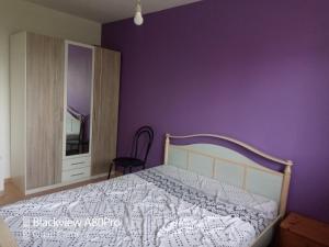 ein Schlafzimmer mit einem Bett und einer lila Wand in der Unterkunft Maison près de Genève, CERN, et stations de ski in Péron