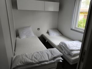 dwa łóżka w małym pokoju z oknem w obiekcie Mobilhome aux dunes de contis w mieście Saint-Julien-en-Born