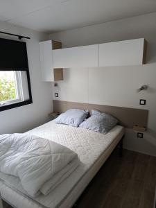 sypialnia z łóżkiem z białą pościelą i oknem w obiekcie Mobilhome aux dunes de contis w mieście Saint-Julien-en-Born