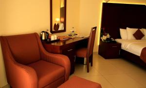 a hotel room with a desk and a bed and a chair at Sohar Beach Hotel in Sohar