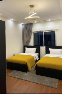 two beds in a bedroom with yellow and white at haya abdun in Amman