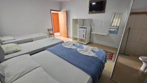 a hospital room with two beds and a refrigerator at Hotel Pousada Aeroporto in Goiânia