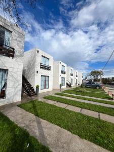 a row of white buildings with grass in front at Hotel La Morada in Treinta y Tres