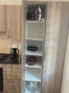 a cupboard in a kitchen with some dishes on it at House For Six Adults in Witbank