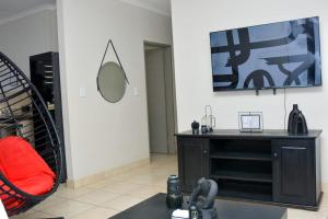 a living room with a red chair and a television at House For Six Adults in Witbank