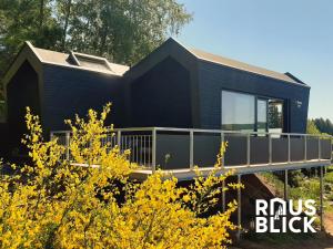 a black house with a deck and yellow flowers at Rausblick Cabin in Bruchweiler-Bärenbach