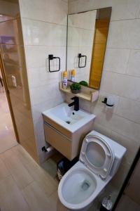 a bathroom with a toilet and a sink and a mirror at Amazing 2BR apartment near the airport in Los Frailes