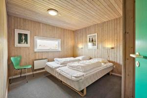 a bedroom with a bed and a green chair at FAN076-Fano-Slunden-123 in Fanø