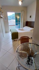 a room with a table and a bed and a window at Pousada Green in Florianópolis