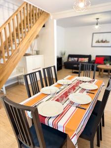 ein Esszimmer mit einem Tisch mit Stühlen und einer Treppe in der Unterkunft Maison avec Terrasse 6 pax proche Paris & Disney - Parking in Nogent-sur-Marne